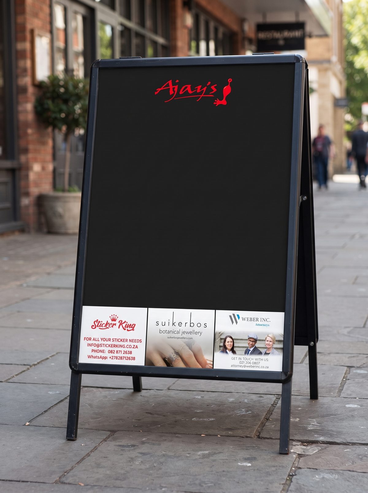 An Audacity Ads A-frame board on a pavement, with the venue's logo at the top and three local business ads along the bottom